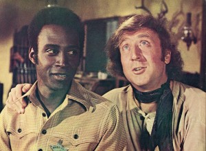 Actor Gene Wilder (right) puts his arm around the shoulder of Cleavon Little in a still from the film, 'Blazing Saddles,' directed by Mel Brooks, 1974. (Photo by Warner Bros./Courtesy of Getty Images)